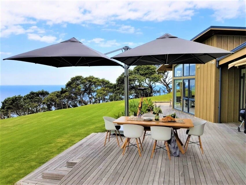Multi canopy black umbrella covers a table next to landscape view