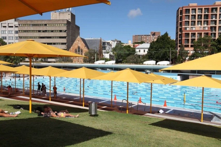 UltraShade - Heavy Duty Outdoor Umbrellas with Yellow Canopies by a commercial swimming pool